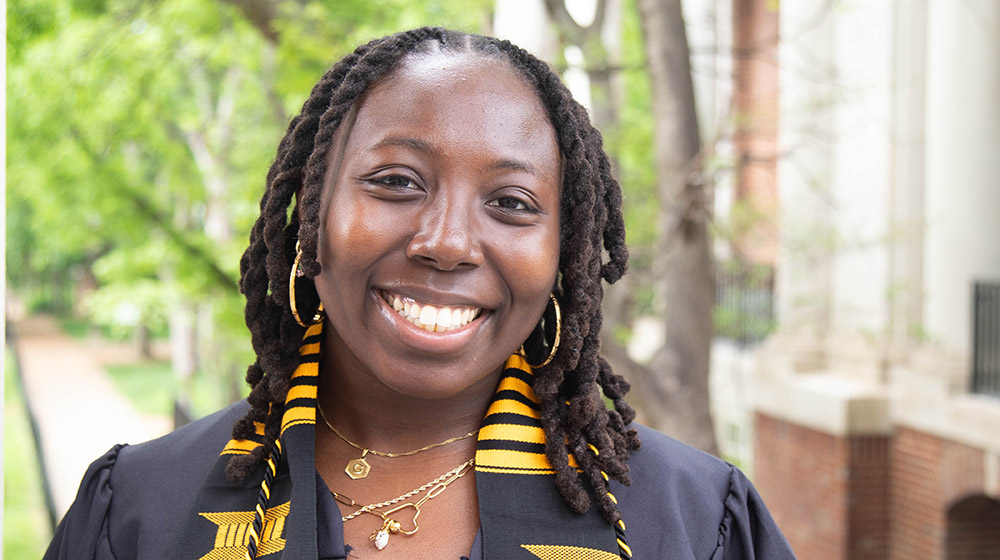 Genevieve Harvey standing outside wearing her undergraduate graduation gown